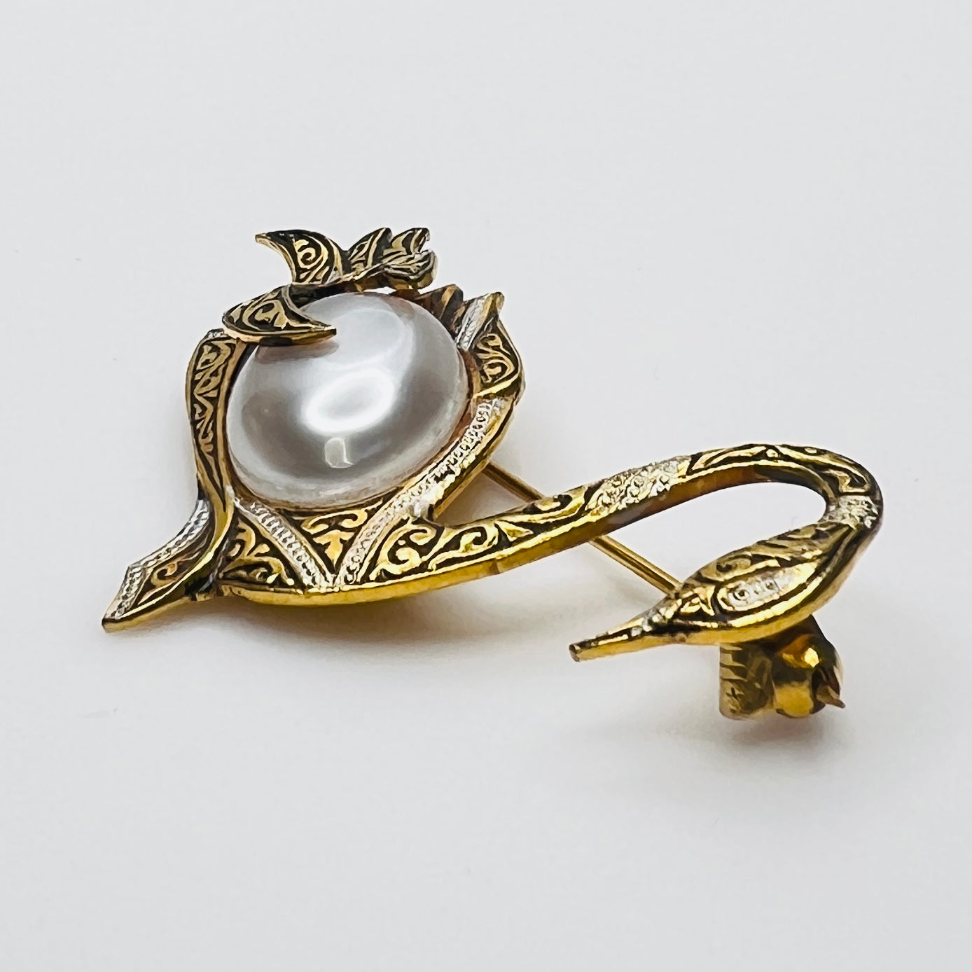 Side view of vintage swan brooch with faux pearl cabochon center