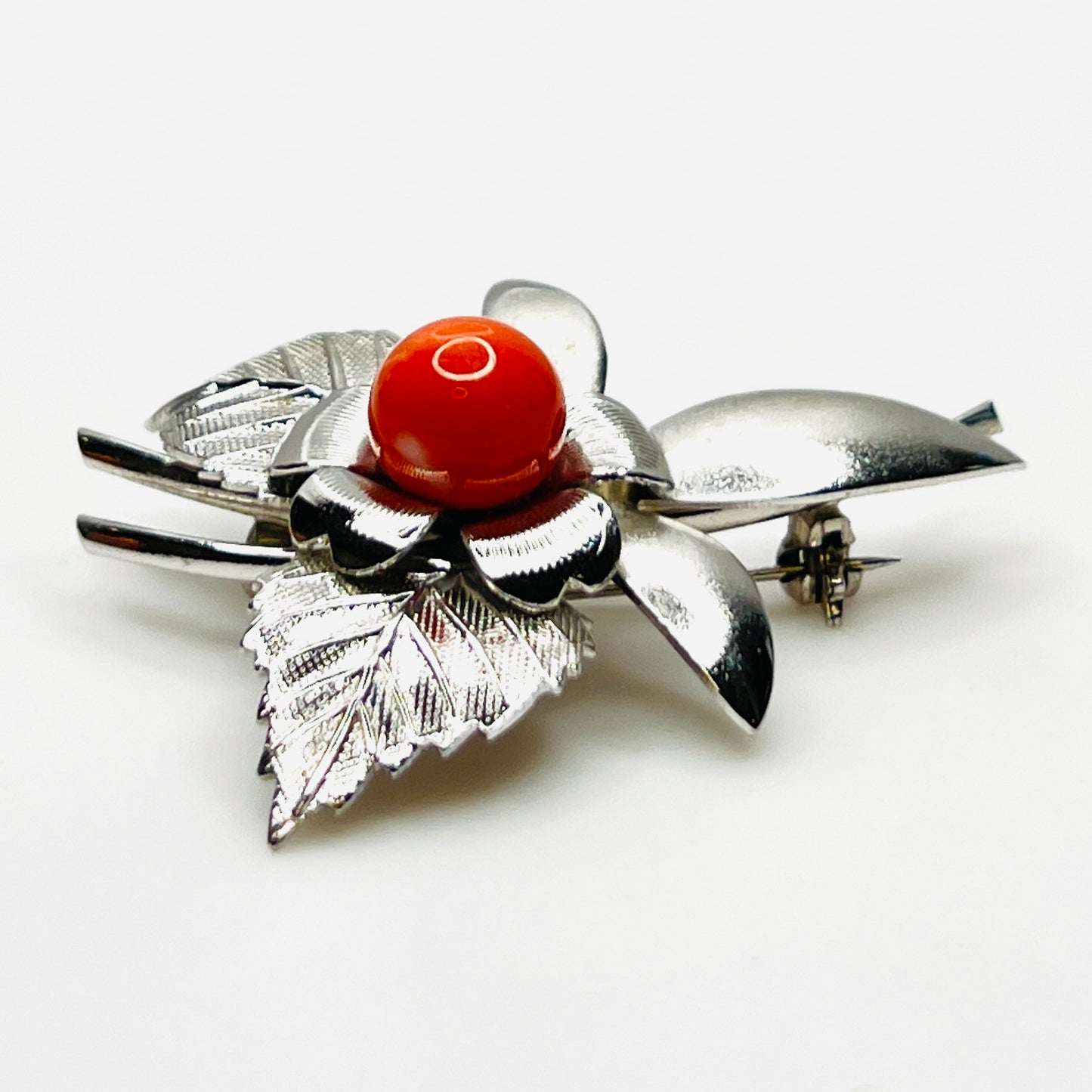 Side profile of vintage stainless steel flower brooch with orange cabochon center