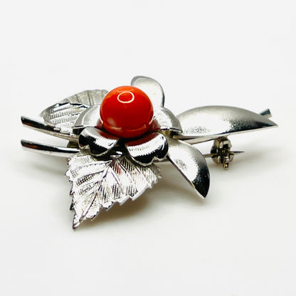 Side profile of vintage stainless steel flower brooch with orange cabochon center