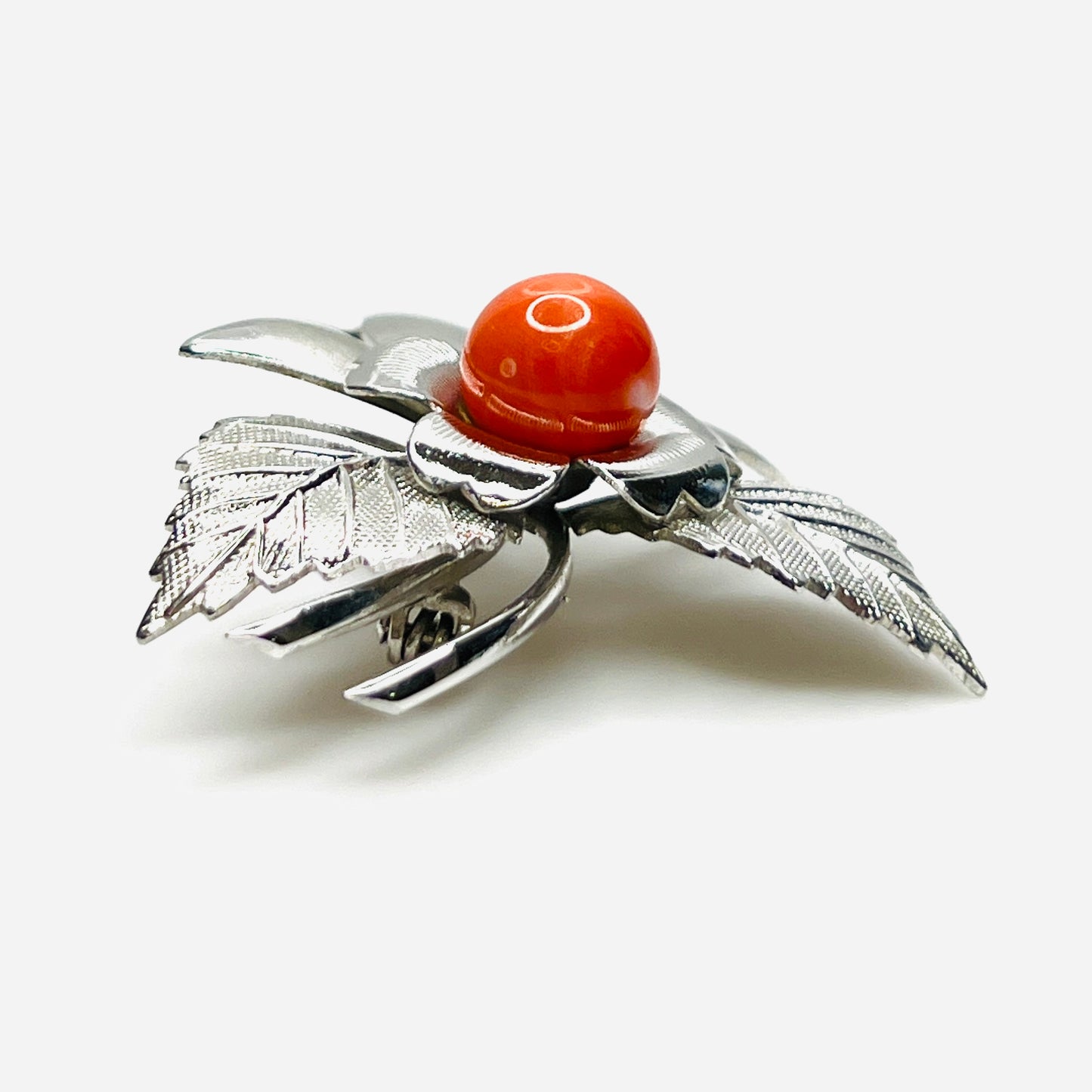 Side profile of vintage stainless steel flower brooch with orange cabochon center