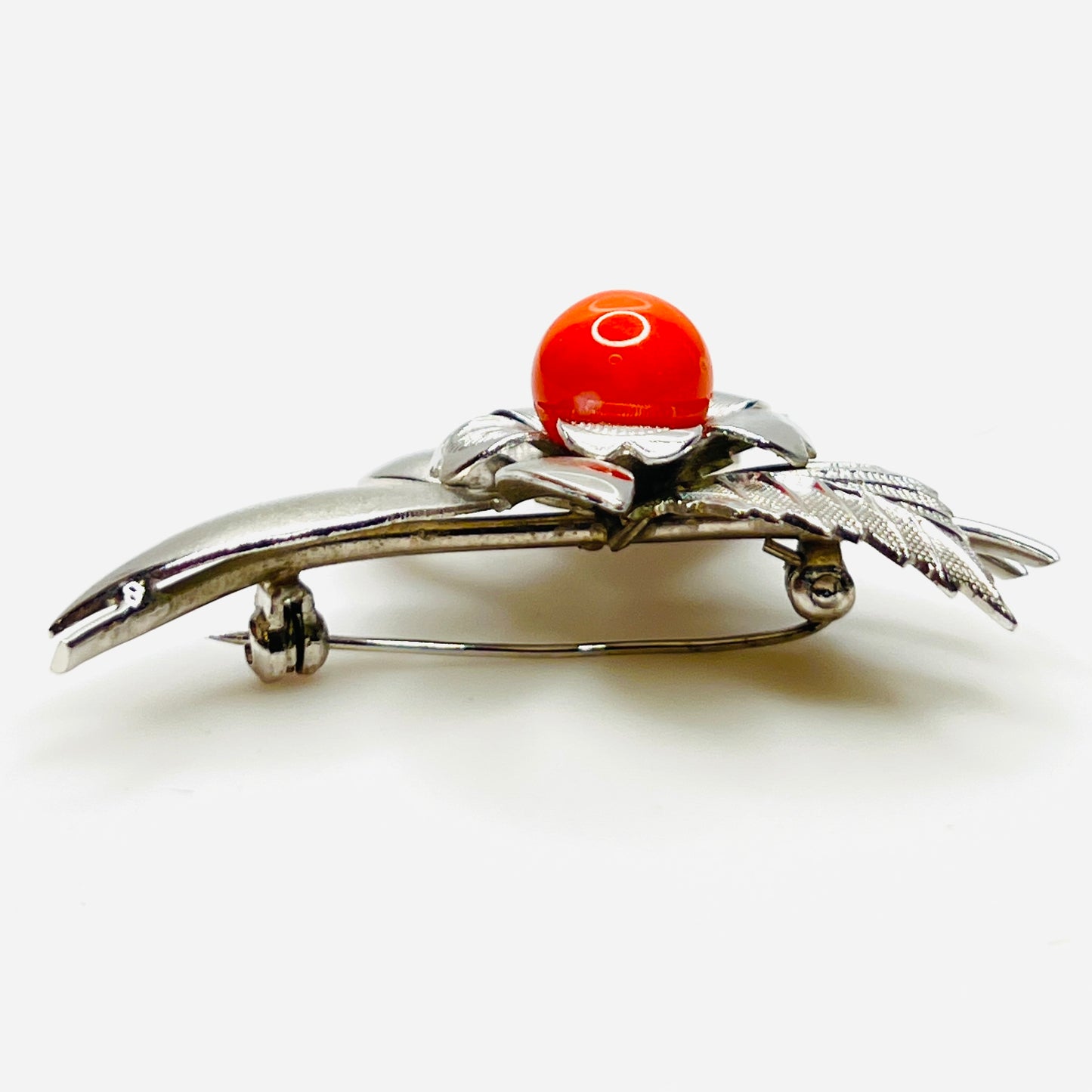 Side profile of vintage stainless steel flower brooch with orange cabochon center