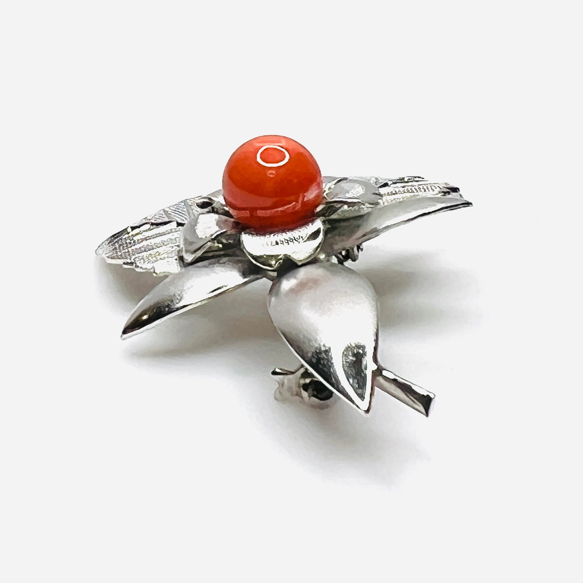 Side profile of vintage stainless steel flower brooch with orange cabochon center