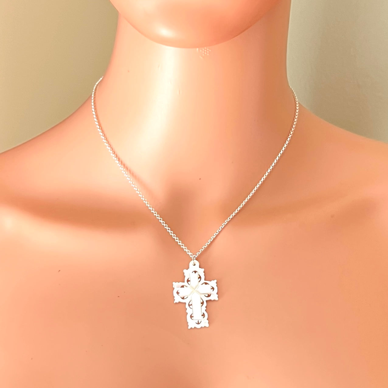 Vintage Mother of Pearl Bethlehem cross necklace worn on mannequin with sterling silver chain.
