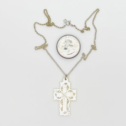 Hand-carved Mother of Pearl Bethlehem cross necklace with quarter for size comparison.