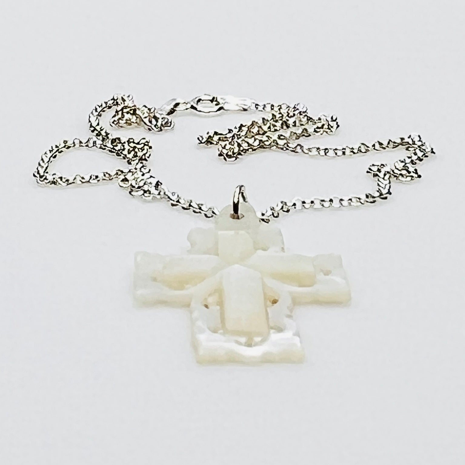 Side profile of vintage Mother of Pearl cross pendant on sterling silver chain.
