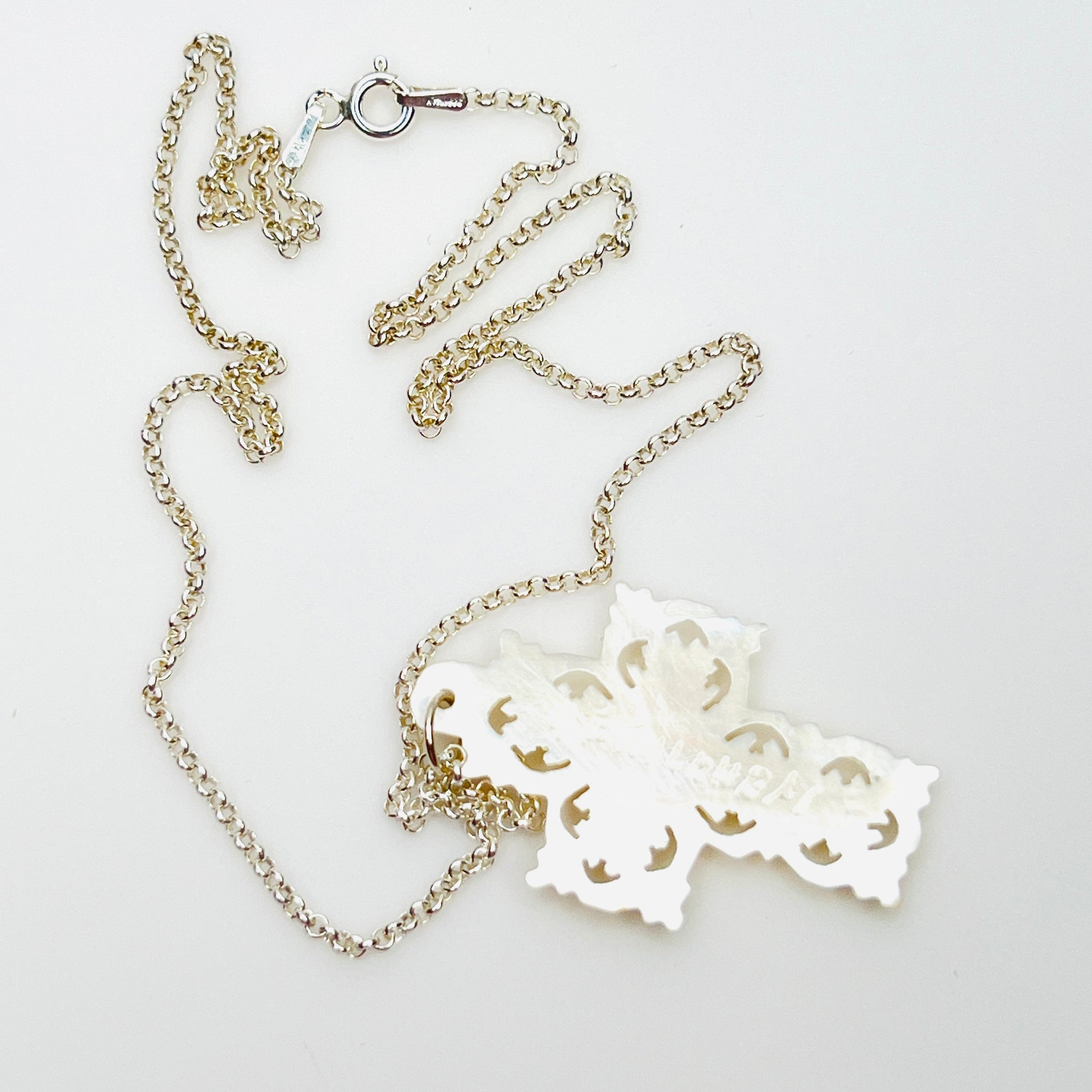 Reverse of Bethlehem Mother of Pearl cross pendant showing carved back and sterling chain.