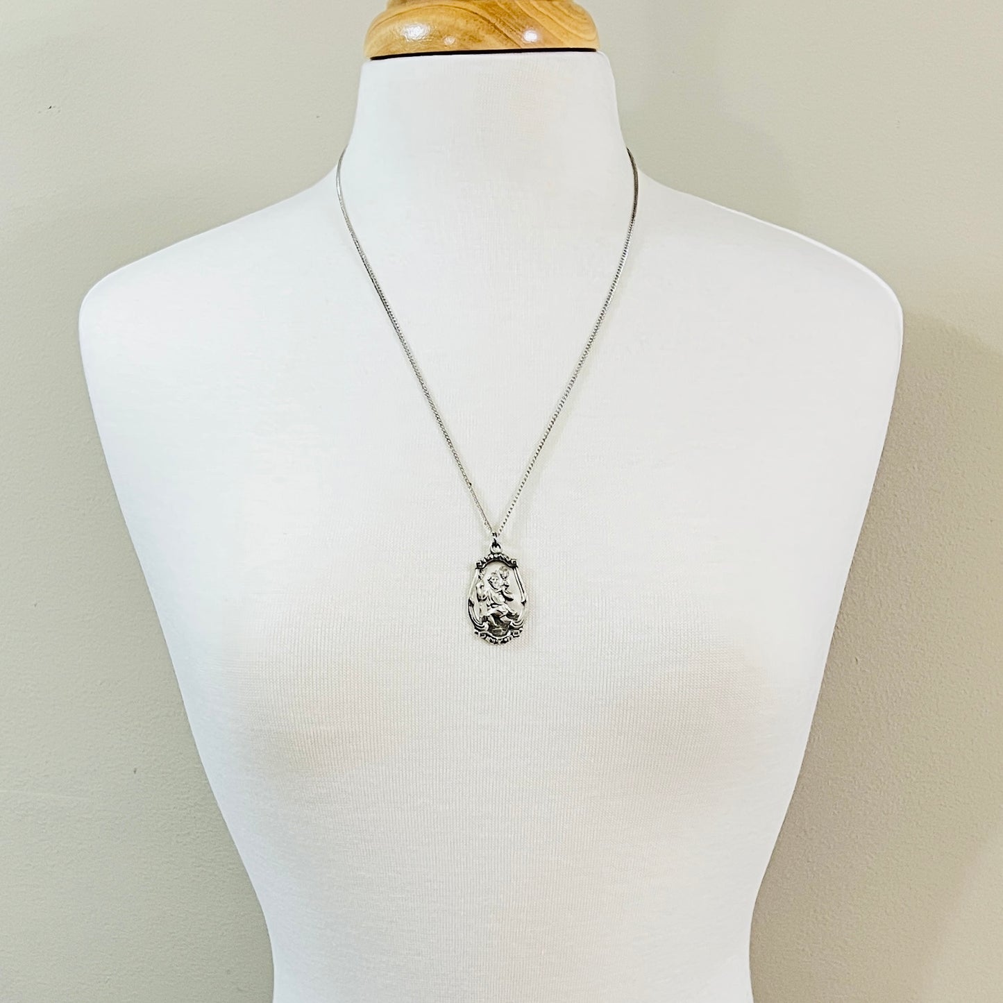 Vintage sterling St. Christopher pendant necklace displayed on jewelry bust.