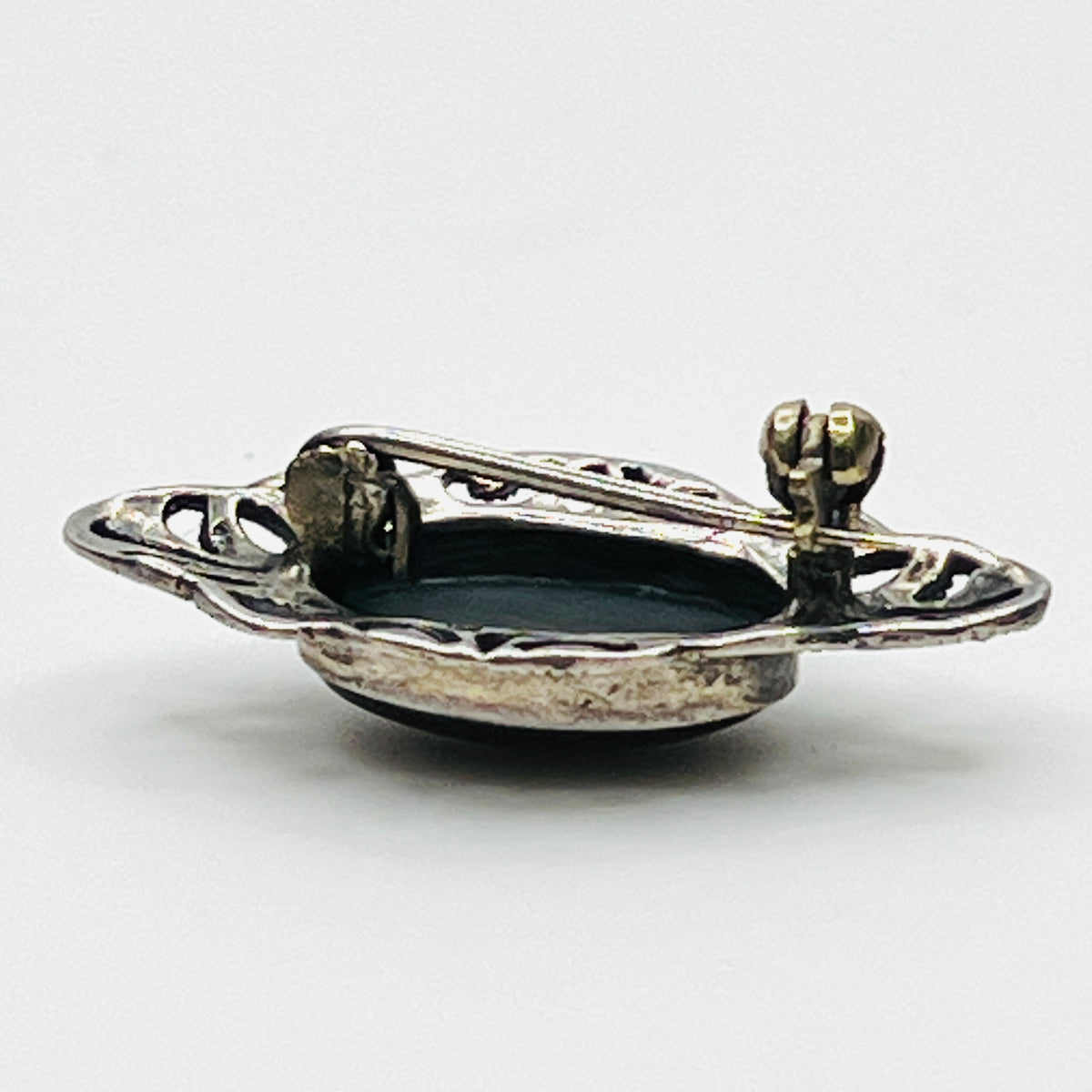 Reverse of vintage sterling silver black onyx brooch showing openwork construction and rollover pin clasp.