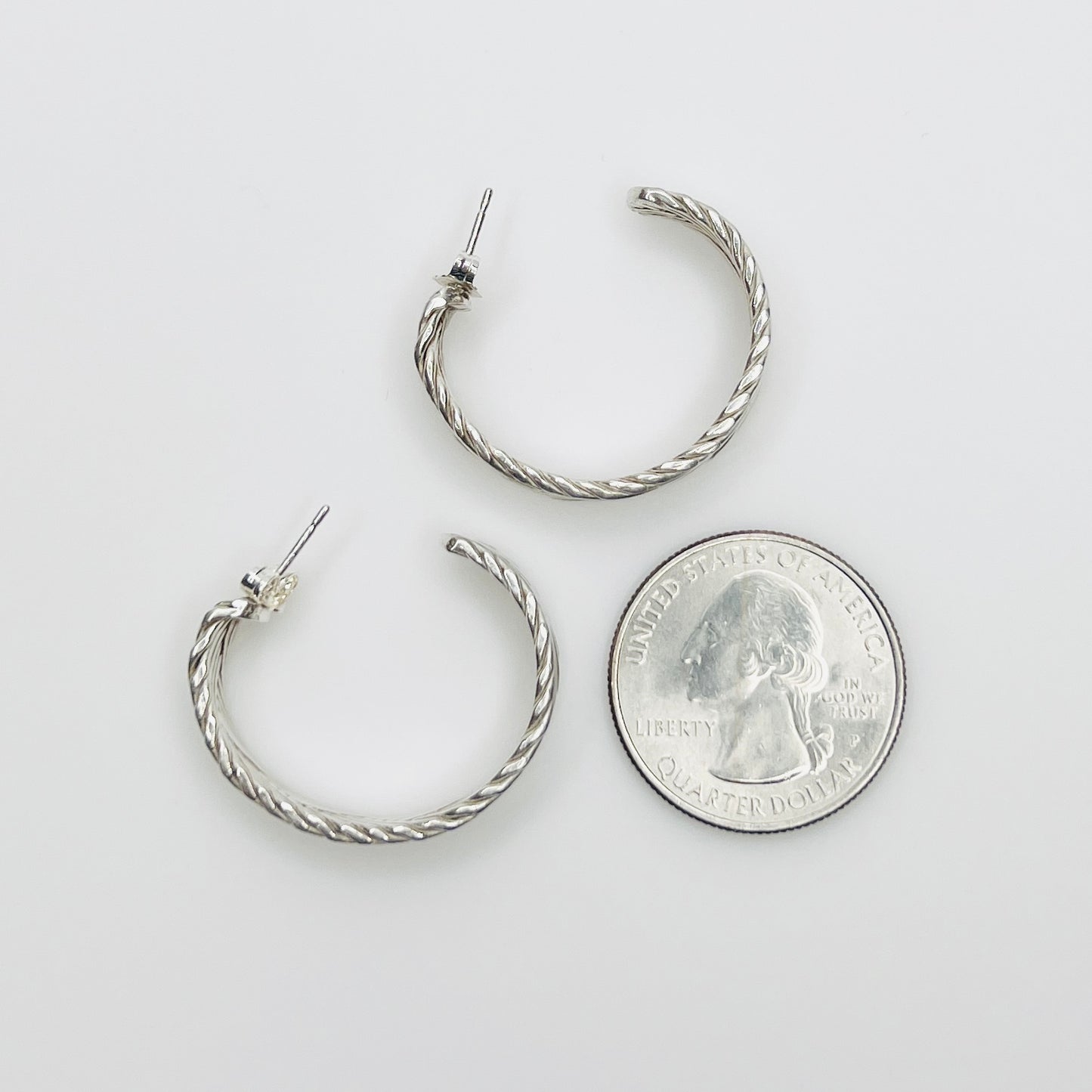 Sterling silver hoop earrings beside quarter for size reference