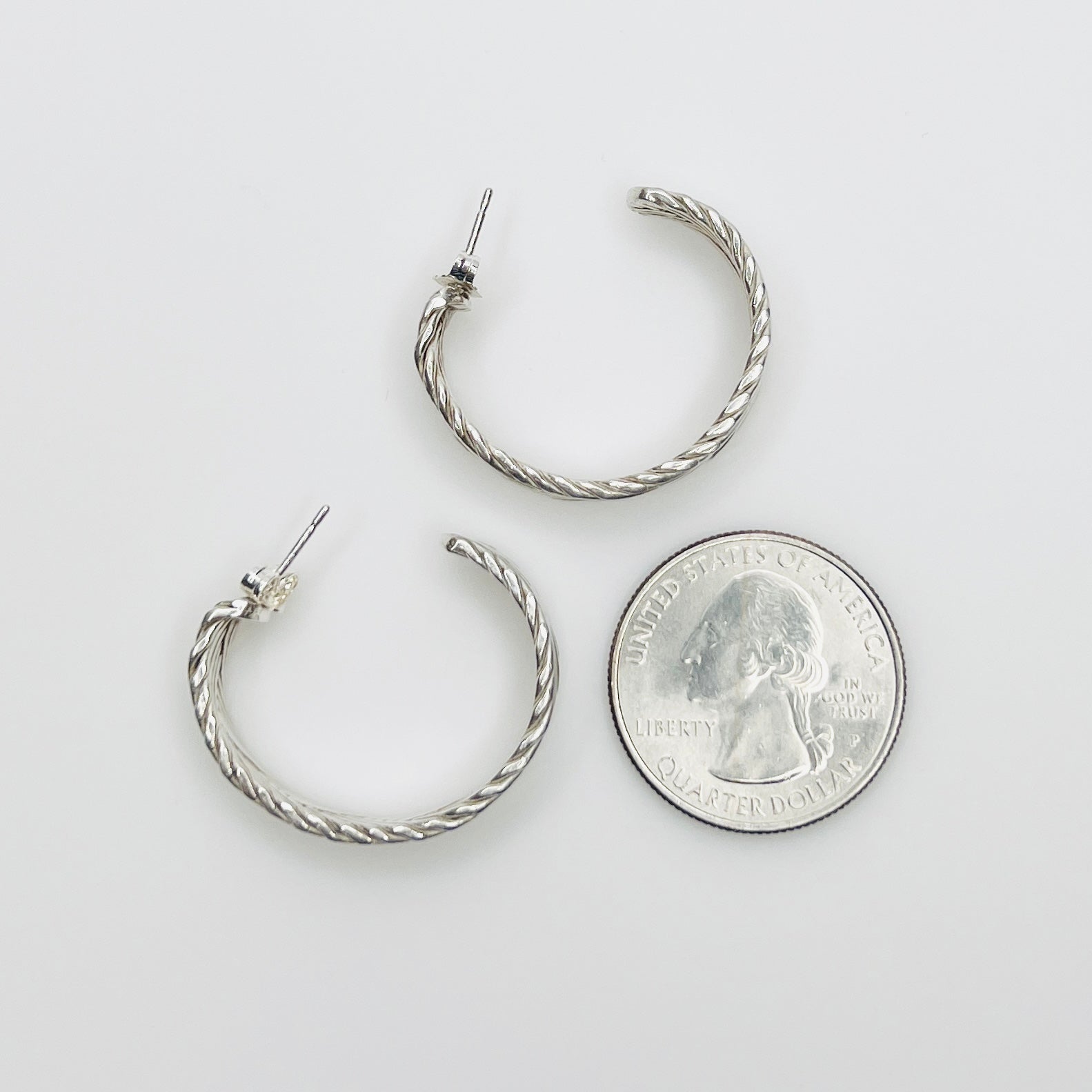 Sterling silver hoop earrings beside quarter for size reference