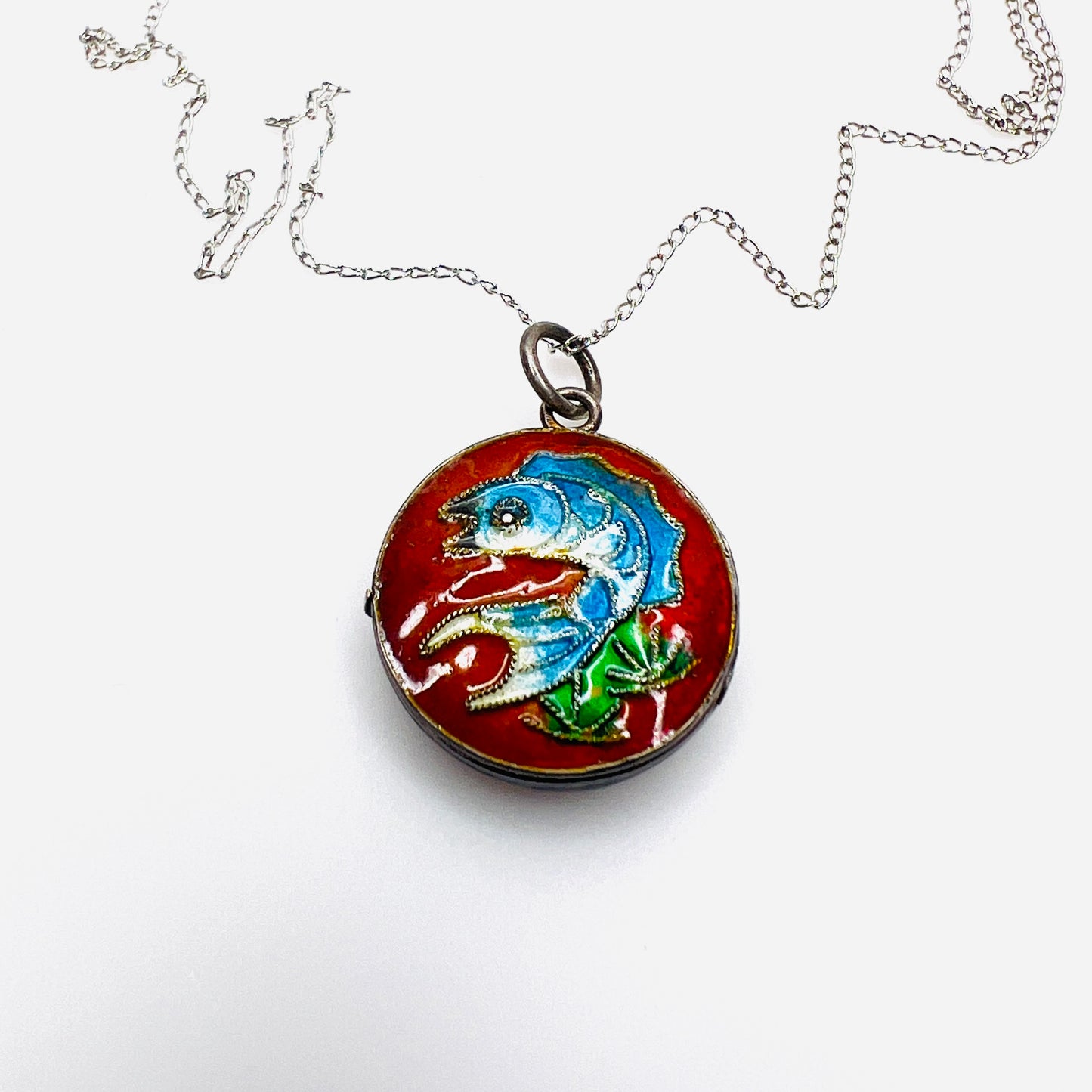 Close-up of vintage sterling silver cloisonné koi fish enamel locket.
