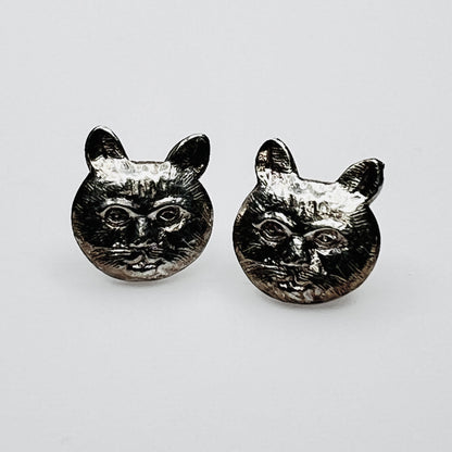 Close-up of silver cat earrings showing facial detail
