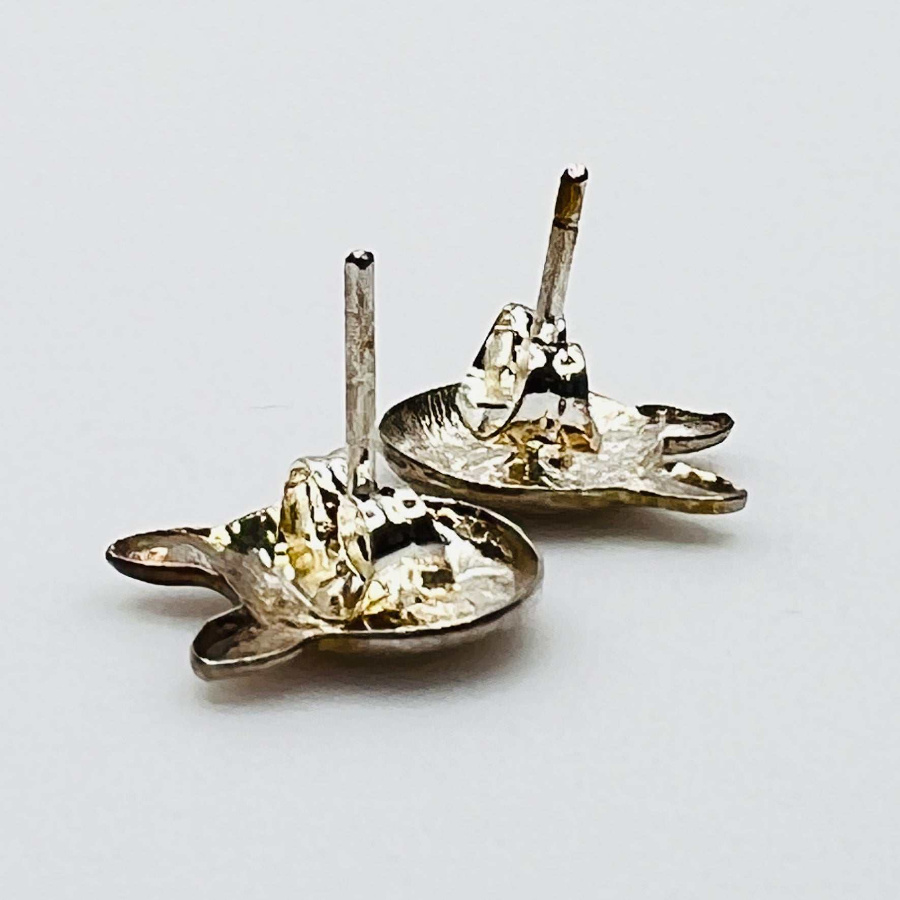 Close-up of silver cat earrings showing facial detail