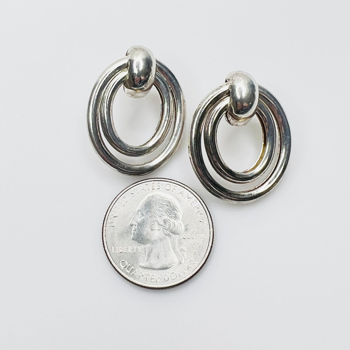 Vintage 925 sterling silver oval earrings beside quarter for scale