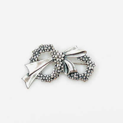 Vintage sterling silver floral wreath bow brooch with detailed daisy flowers, circa 1960s.