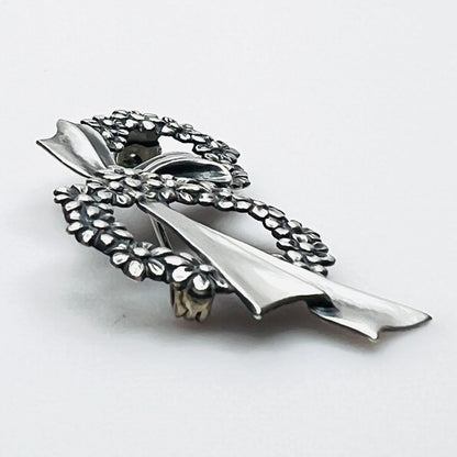 Side profile of vintage sterling silver floral wreath bow brooch with dimensional design.