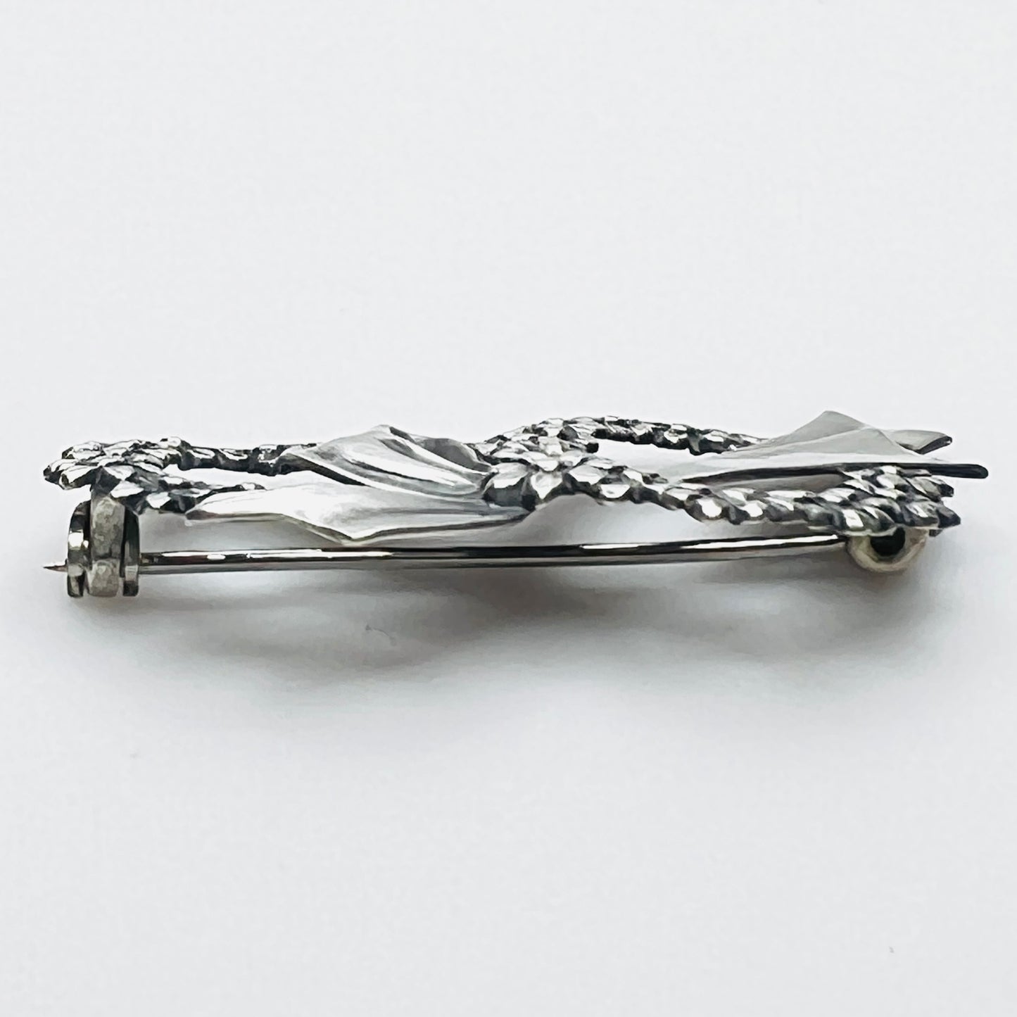 Side profile of vintage sterling silver floral wreath bow brooch with dimensional design.