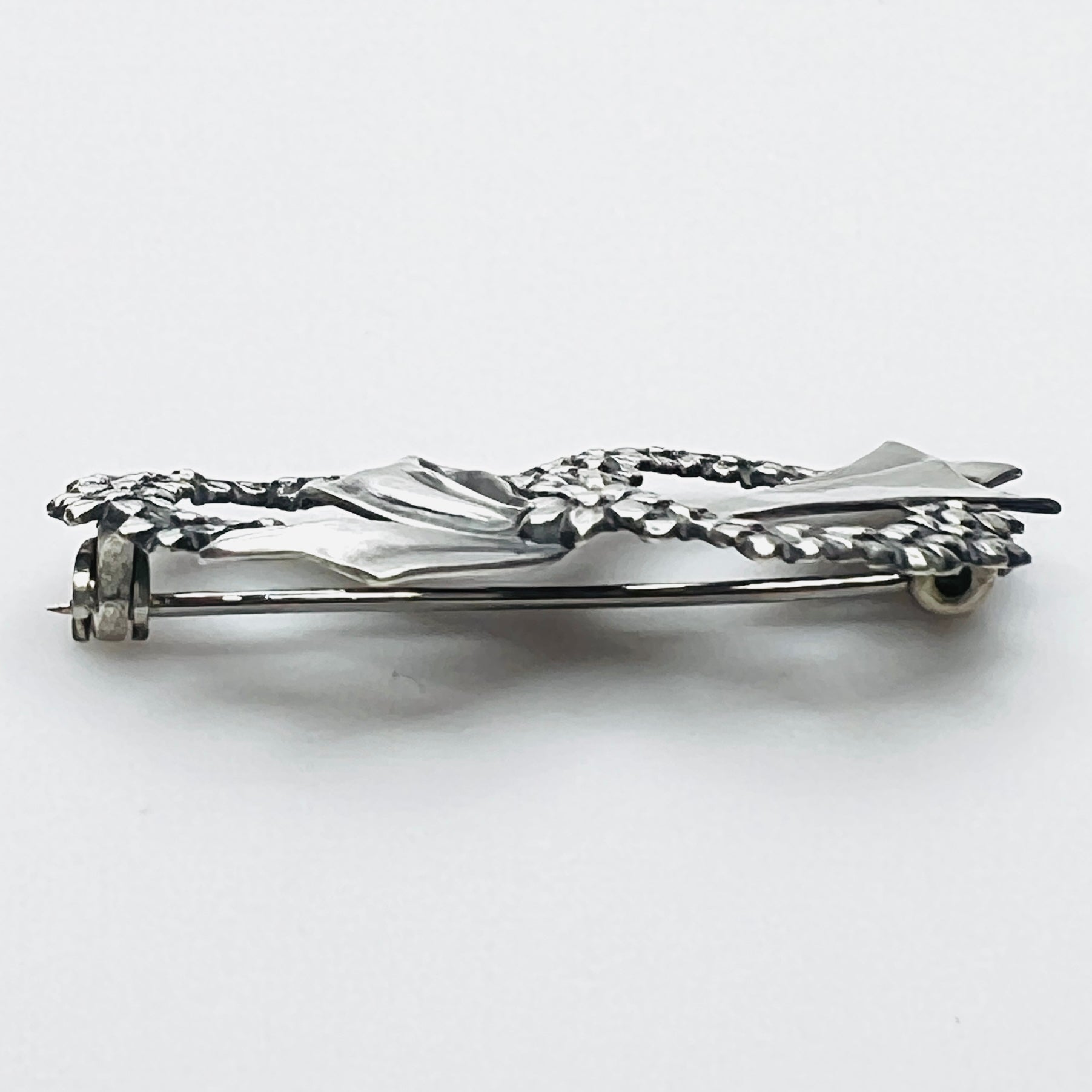 Side profile of vintage sterling silver floral wreath bow brooch with dimensional design.