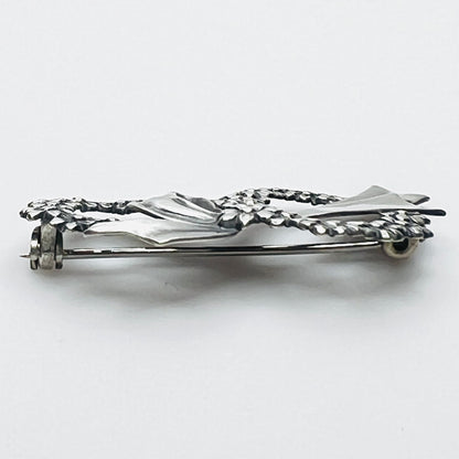Side profile of vintage sterling silver floral wreath bow brooch with dimensional design.