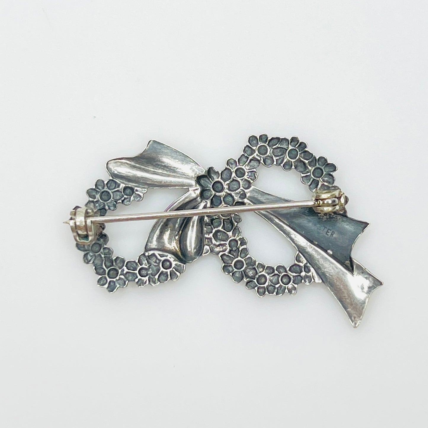 Reverse of vintage sterling silver floral wreath brooch showing pin clasp and sterling mark.