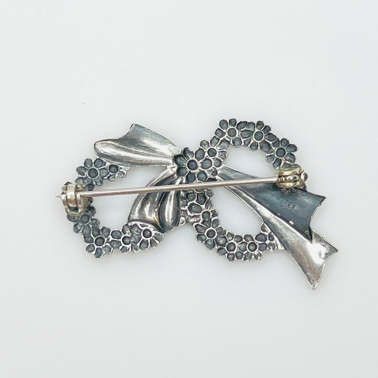 Reverse of vintage sterling silver floral wreath brooch showing pin clasp and sterling mark.