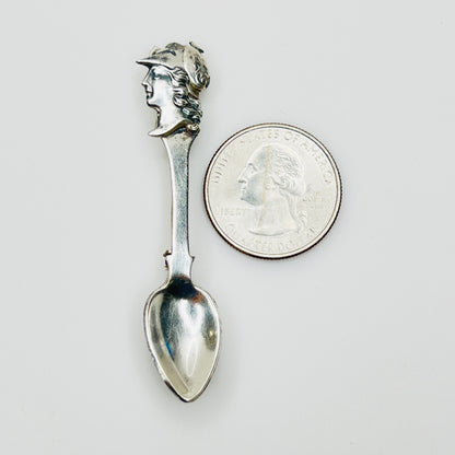 Sterling silver figural spoon pin next to coin for scale