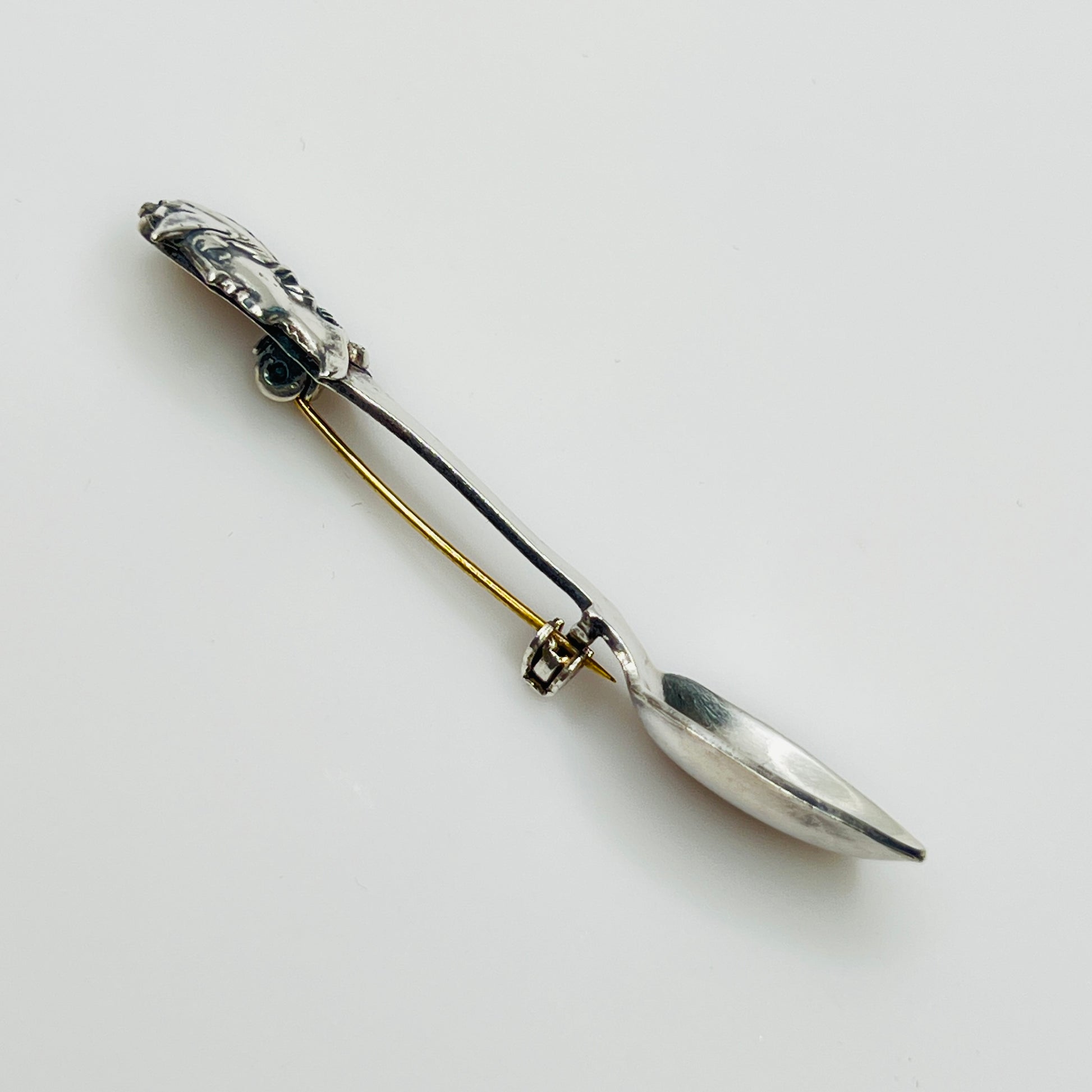 Side view of vintage spoon brooch with helmeted figure