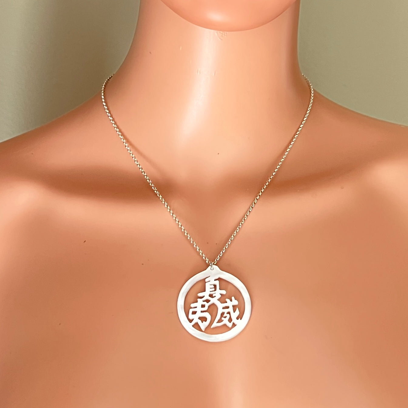 Vintage Mother of Pearl longevity symbol necklace displayed on mannequin.