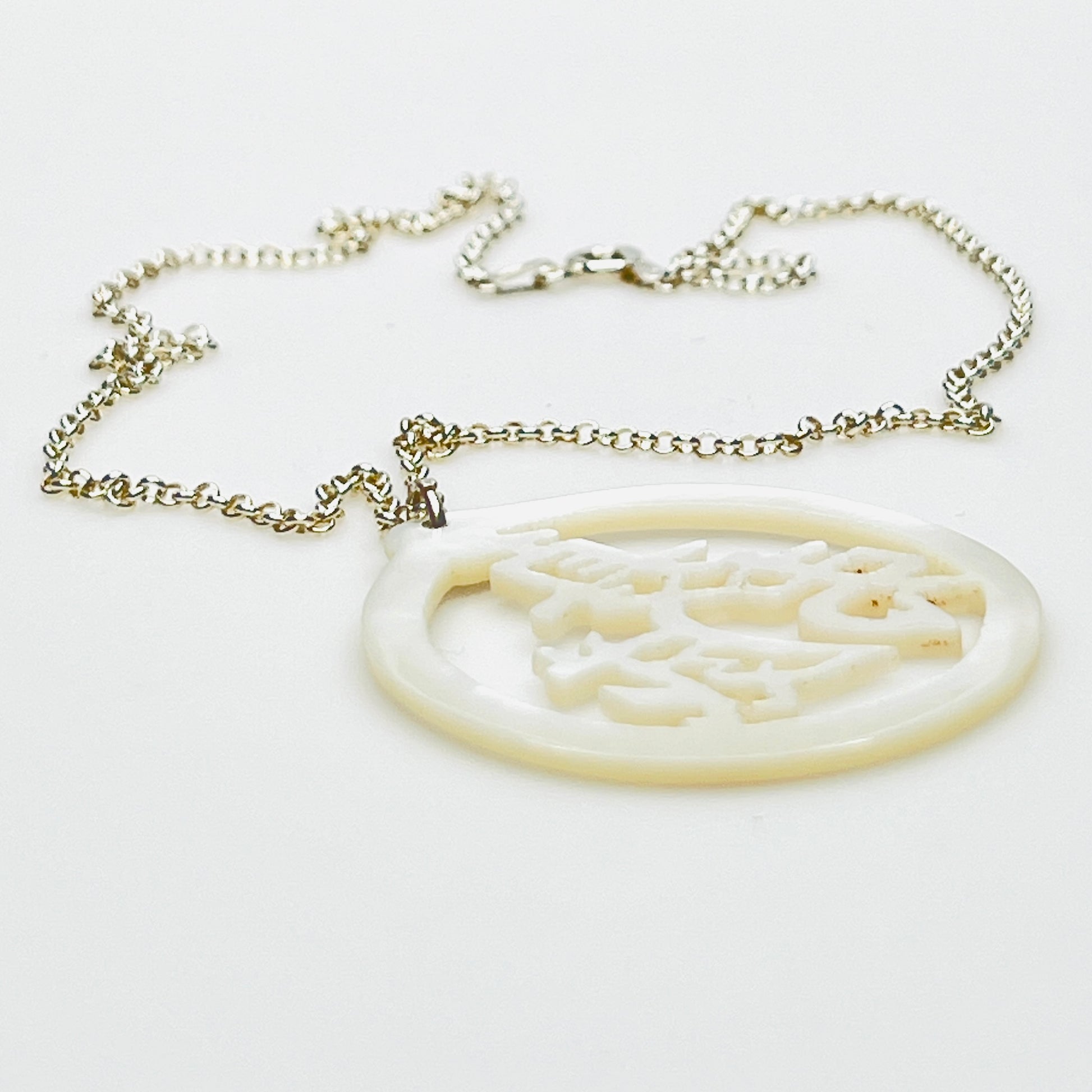 Side profile of carved Mother of Pearl longevity pendant on sterling silver chain.