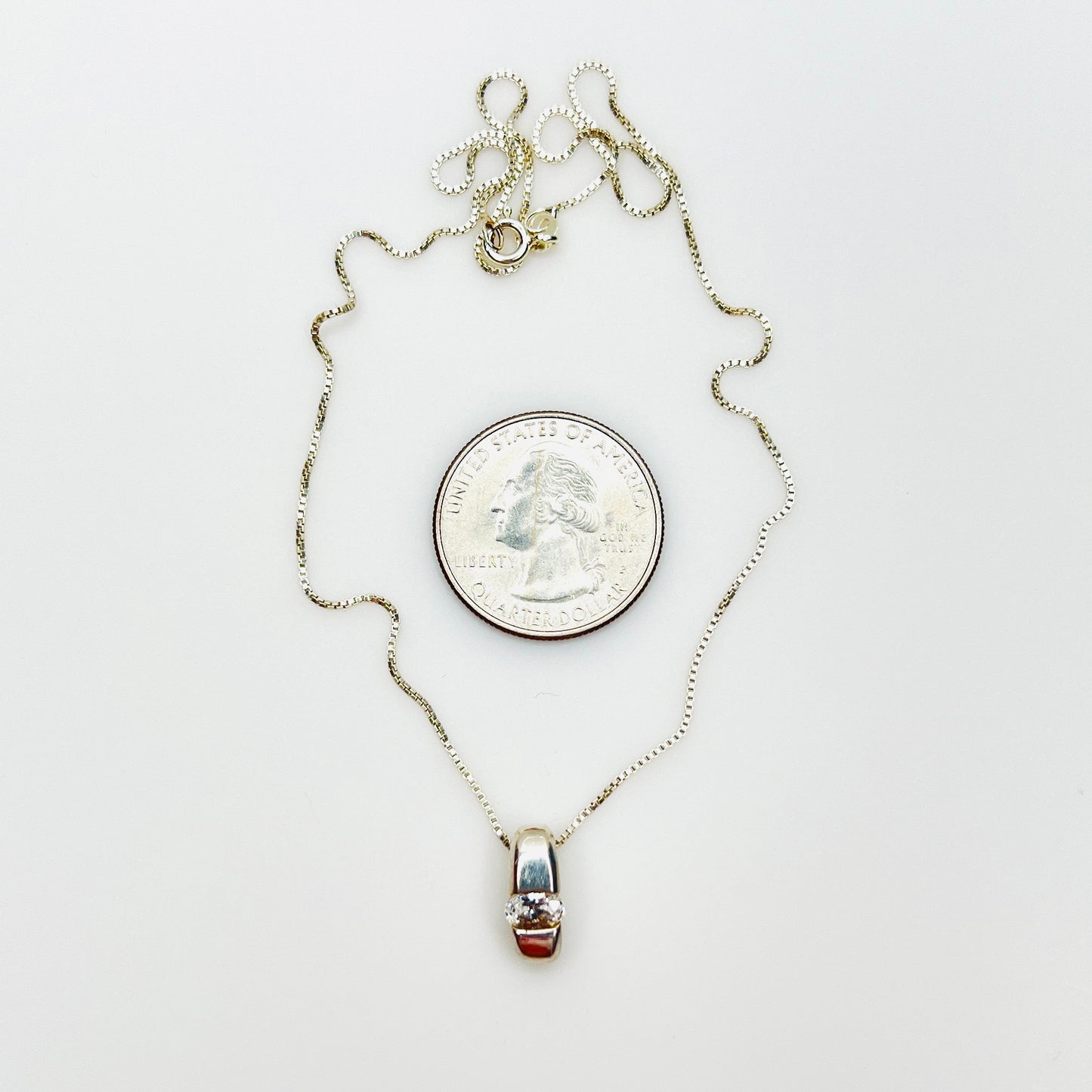Sterling silver CZ pendant necklace beside quarter showing pendant size and 16-inch chain.