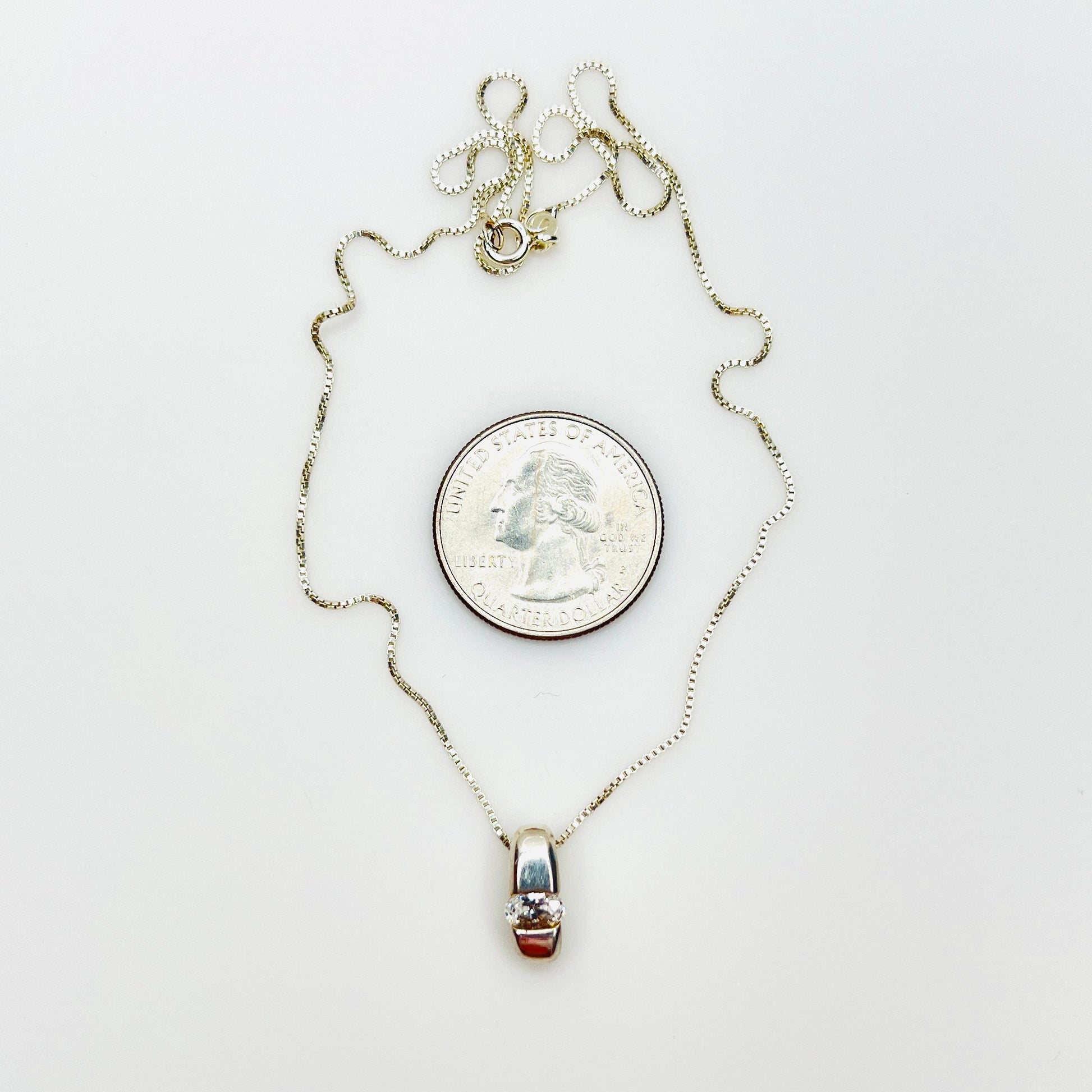 Sterling silver CZ pendant necklace beside quarter showing pendant size and 16-inch chain.