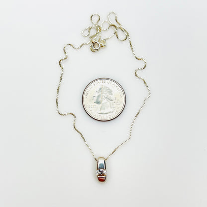 Sterling silver CZ pendant necklace beside quarter showing pendant size and 16-inch chain.