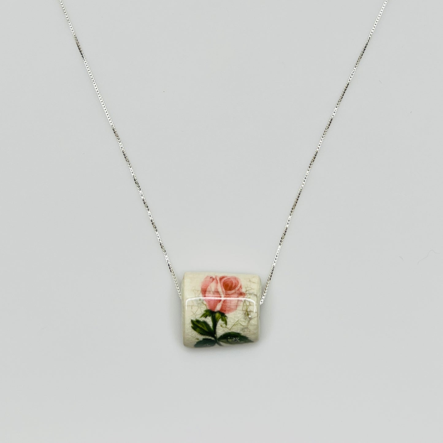 Close-up of pink rose tile pendant with crackle glaze detail
