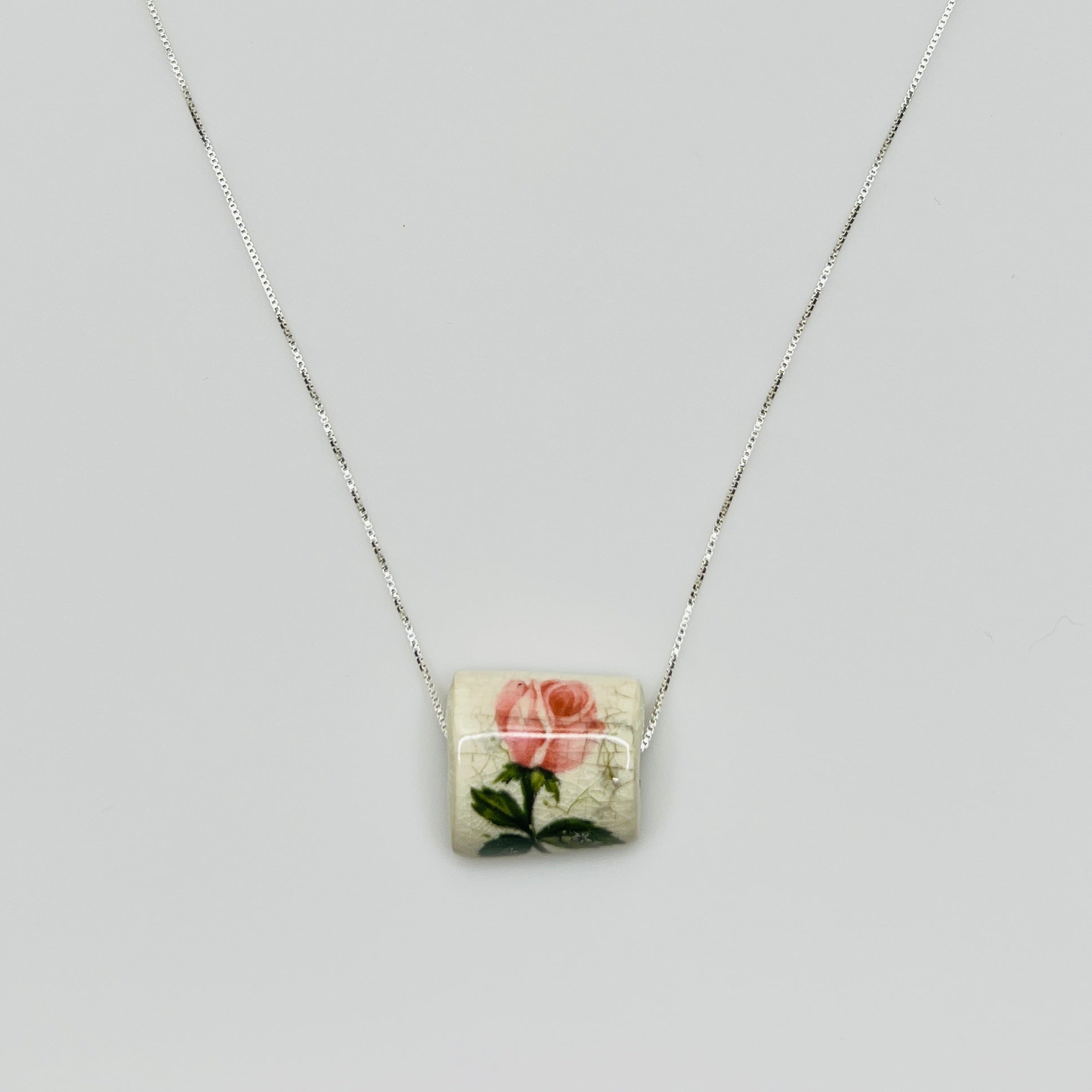 Close-up of pink rose tile pendant with crackle glaze detail