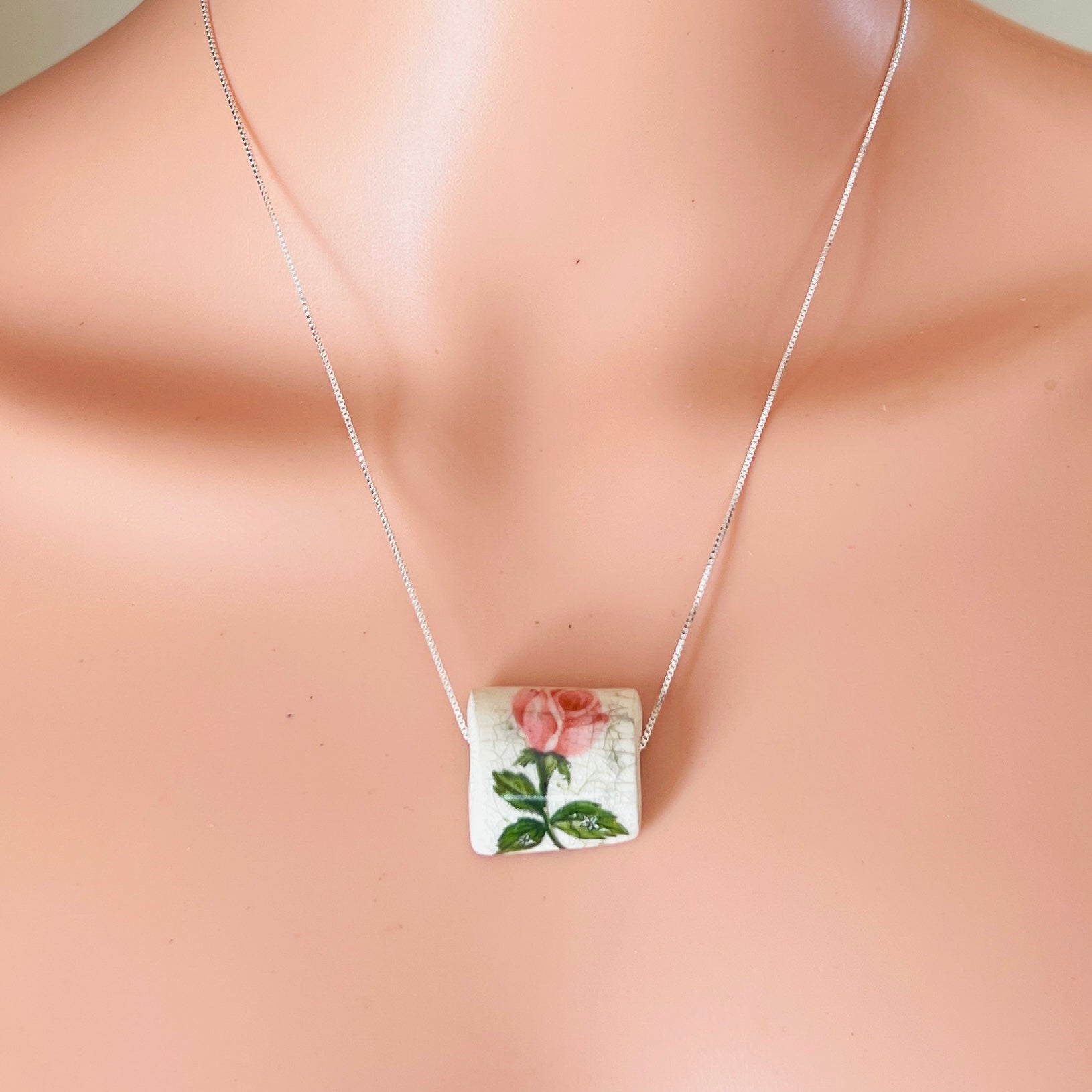 Vintage ceramic rose pendant on silver chain worn on neckline