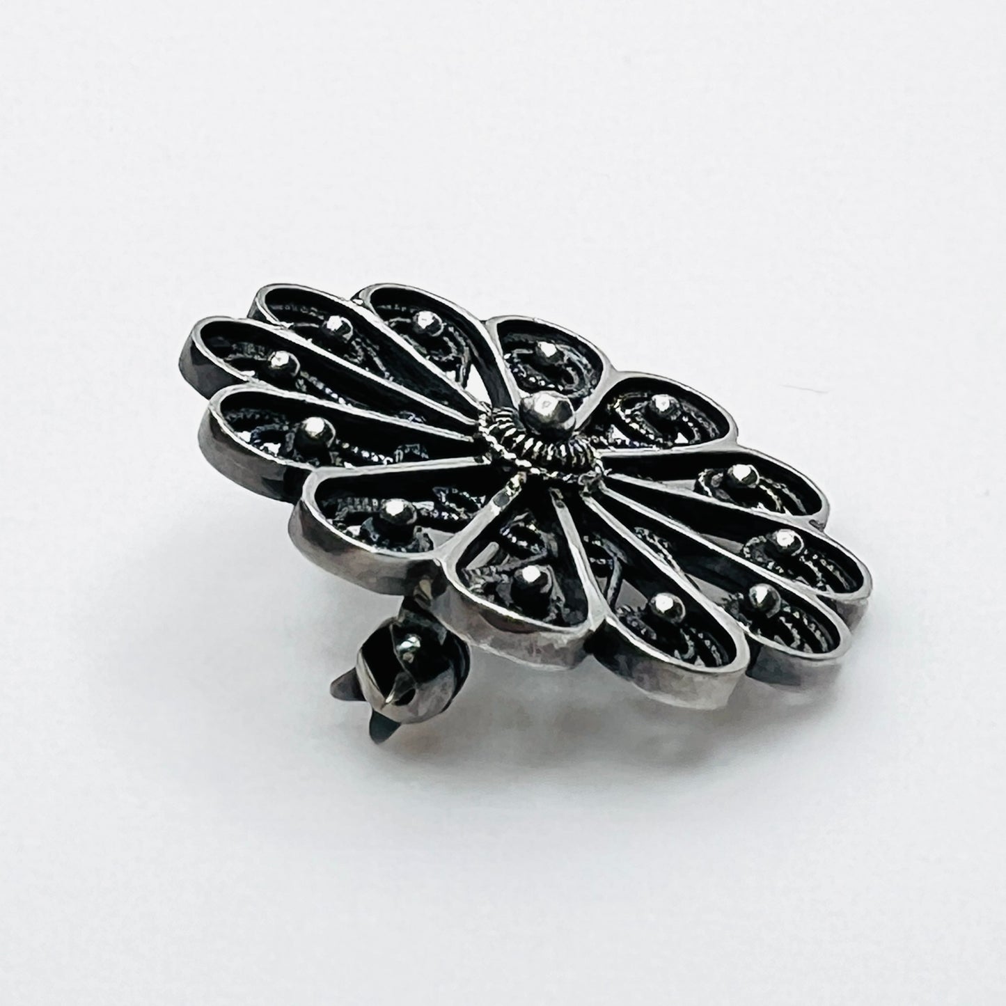 Side profile of vintage sterling silver openwork pinwheel brooch.