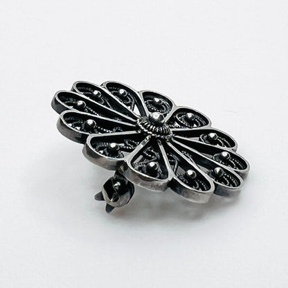 Side profile of vintage sterling silver openwork pinwheel brooch.