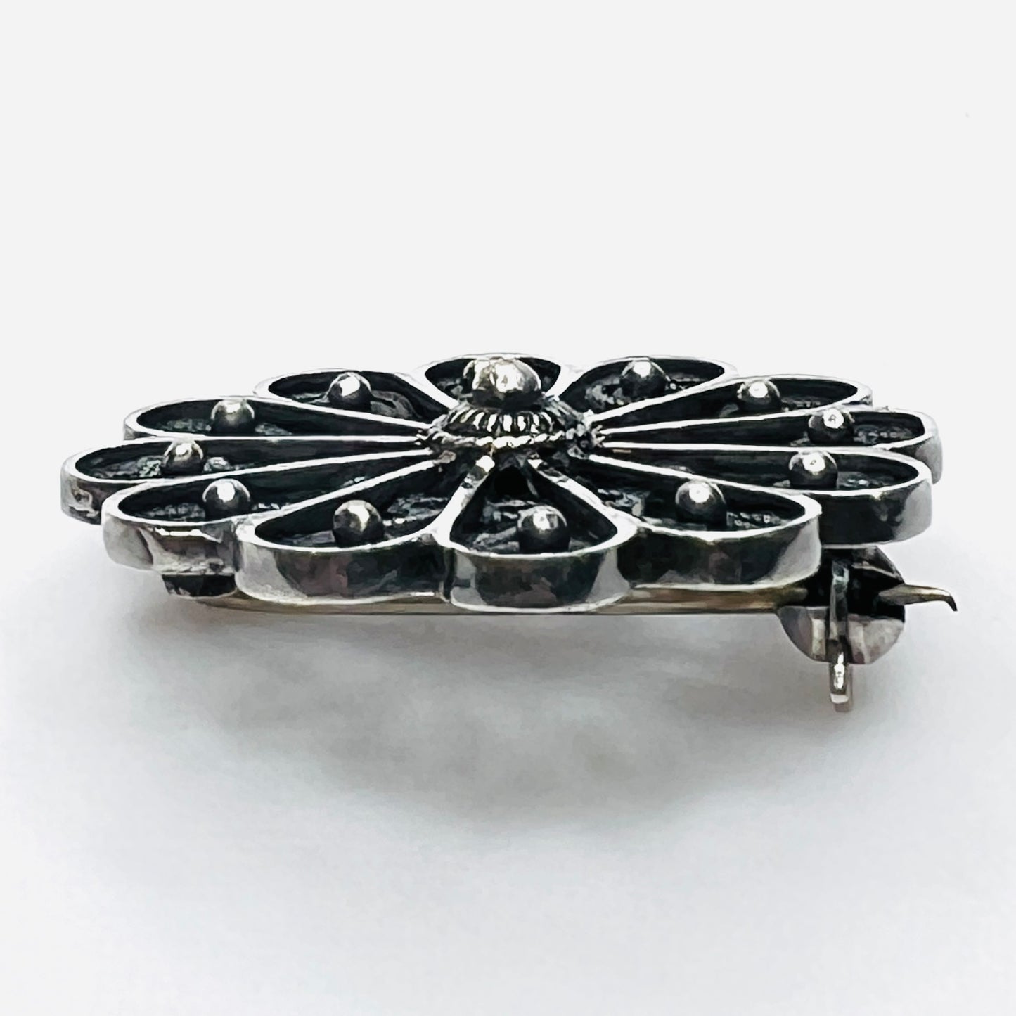 Side profile of vintage sterling silver openwork pinwheel brooch.