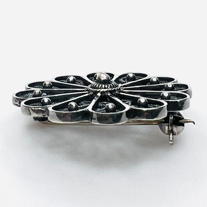 Side profile of vintage sterling silver openwork pinwheel brooch.