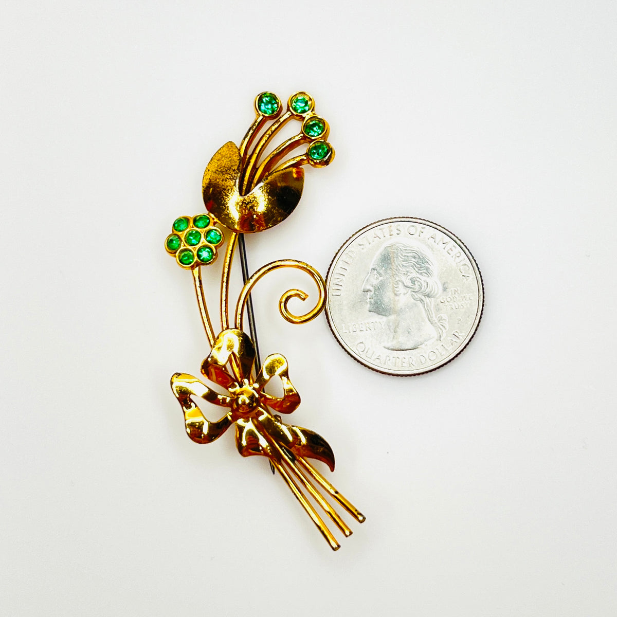 Vintage vermeil sterling green rhinestone flower brooch shown beside quarter