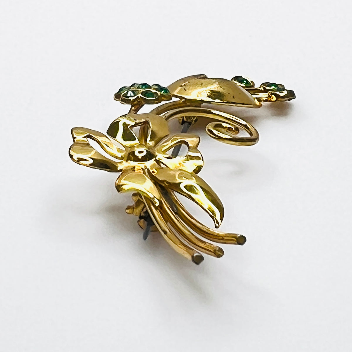Side view of dimensional vermeil sterling floral brooch with green rhinestones
