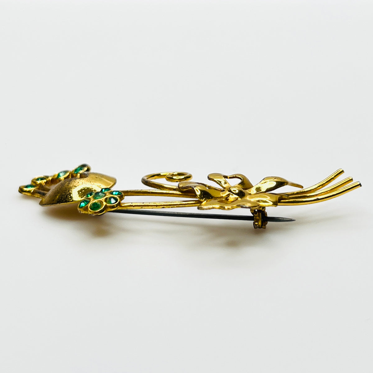 Side view of dimensional vermeil sterling floral brooch with green rhinestones
