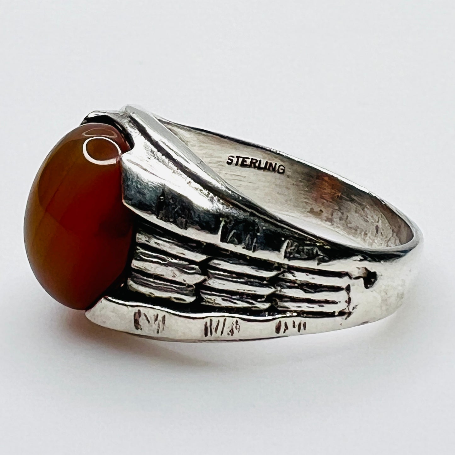 Side view of vintage sterling silver ring with orange carnelian cabochon and sterling stamp