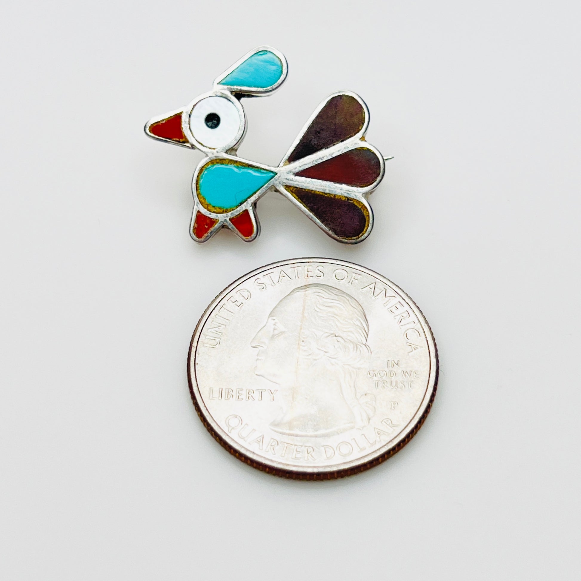 Small sterling silver inlay bird brooch pendant beside quarter for scale, turquoise and mother of pearl