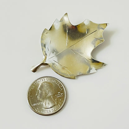 Stuart Nye sterling maple leaf brooch shown beside quarter for scale