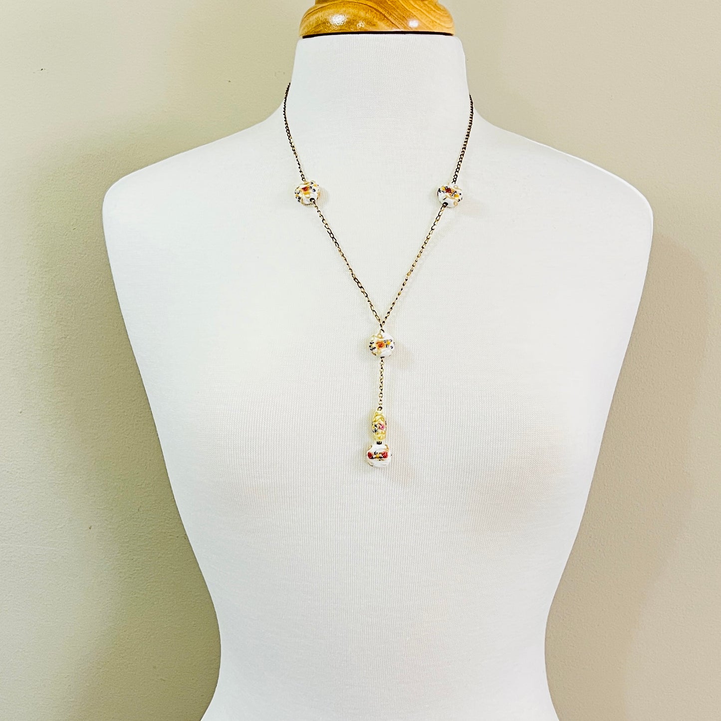 Y style necklace worn on mannequin with white floral glass beads and drop pendant
