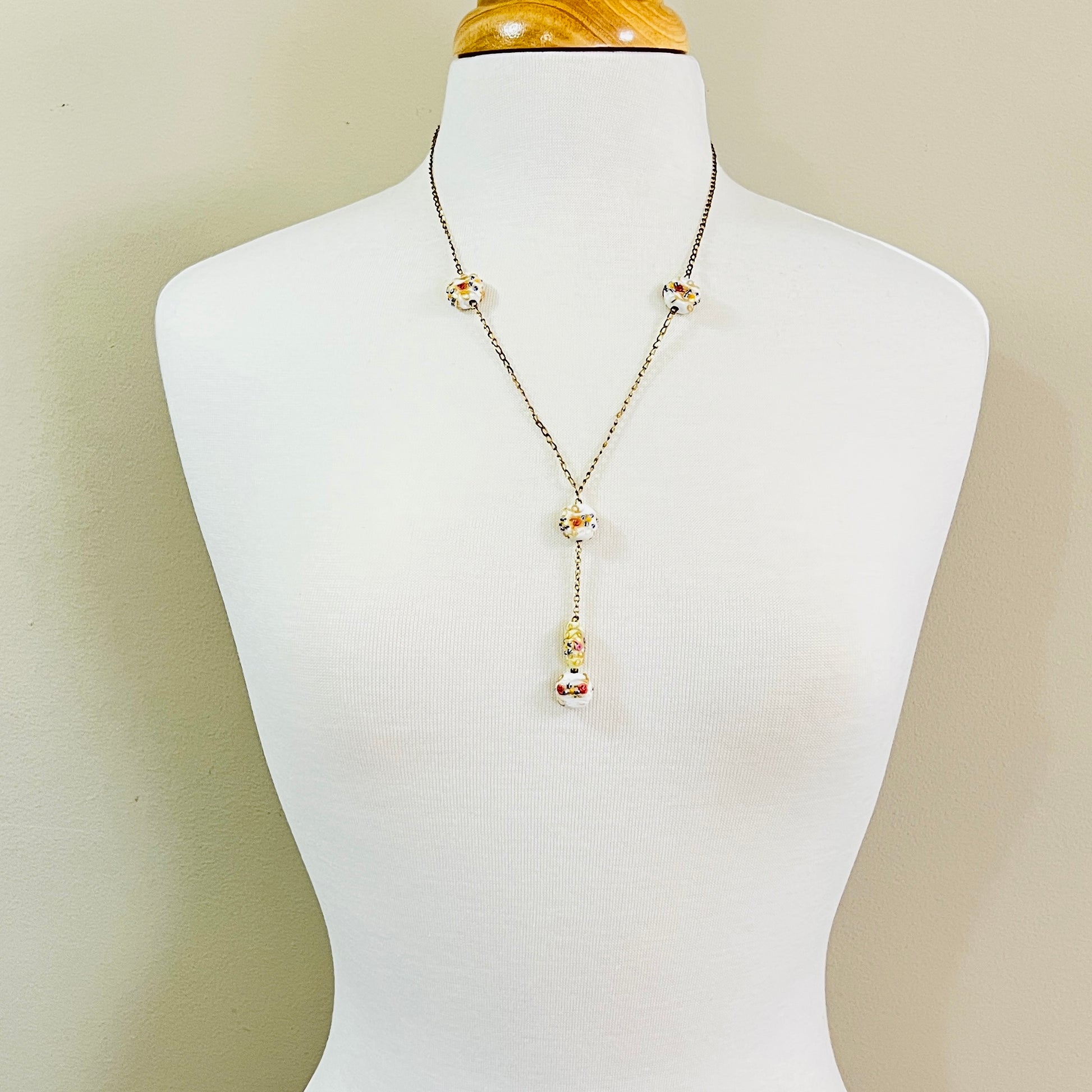 Y style necklace worn on mannequin with white floral glass beads and drop pendant