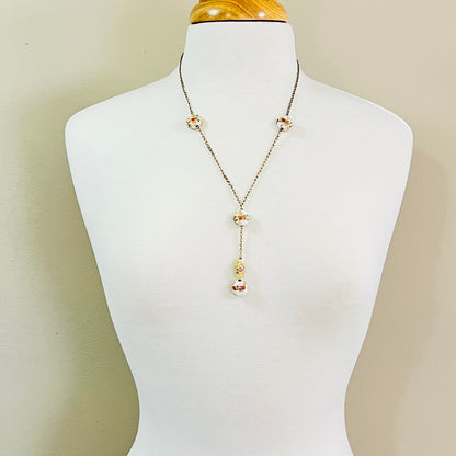 Y style necklace worn on mannequin with white floral glass beads and drop pendant