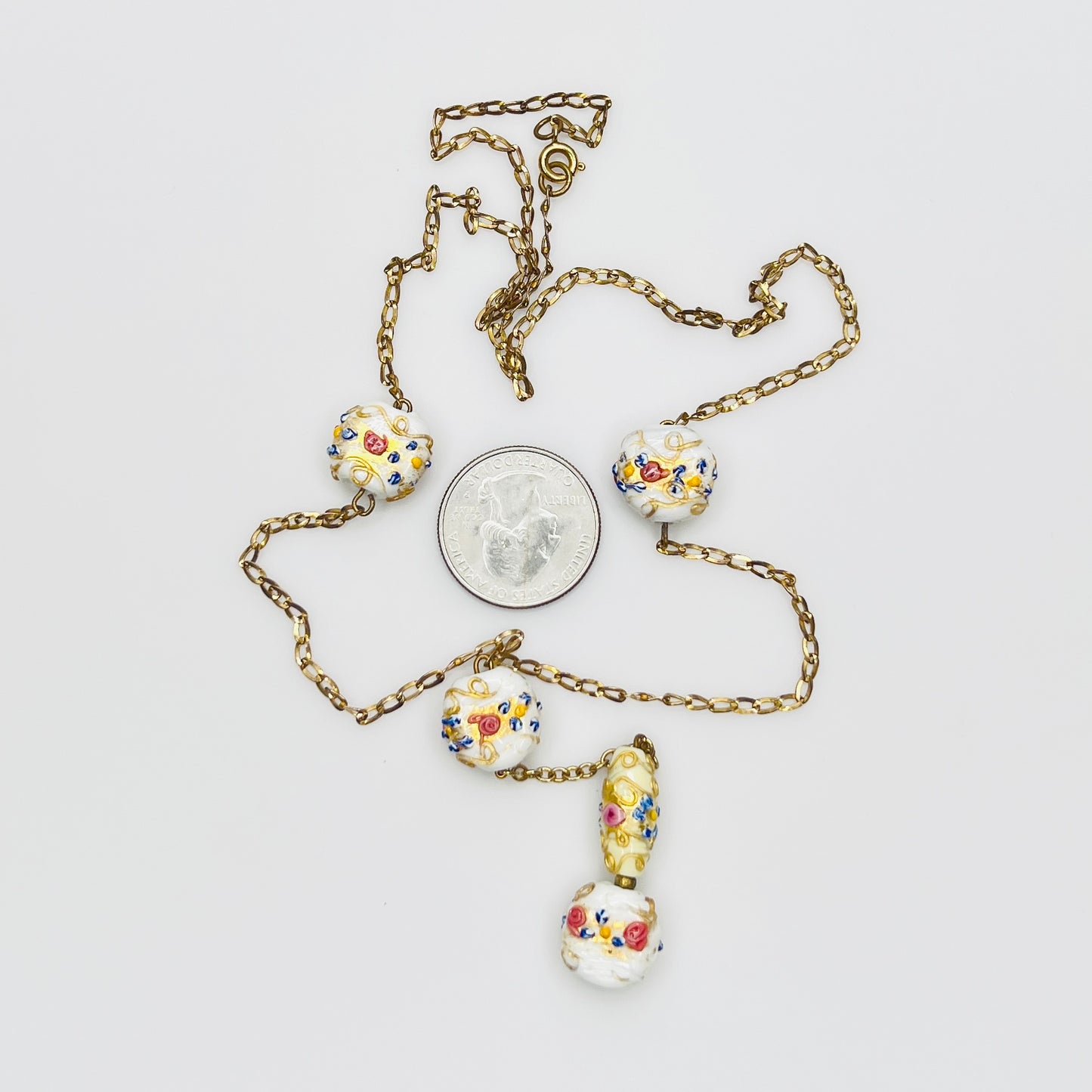 Close-up of Venetian wedding cake beads with multicolor floral details and gold chain