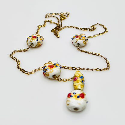 Close-up of Venetian wedding cake beads with multicolor floral details and gold chain